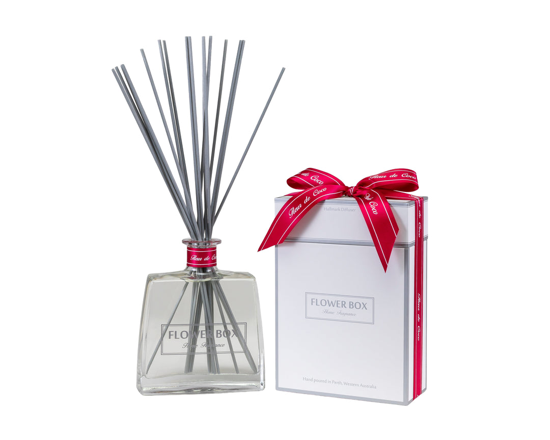 Diffuser with reeds and a wrapped gift box on a white background