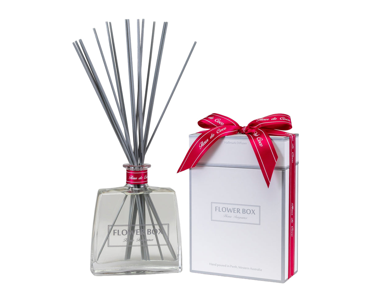 Diffuser with reeds and a wrapped gift box on a white background